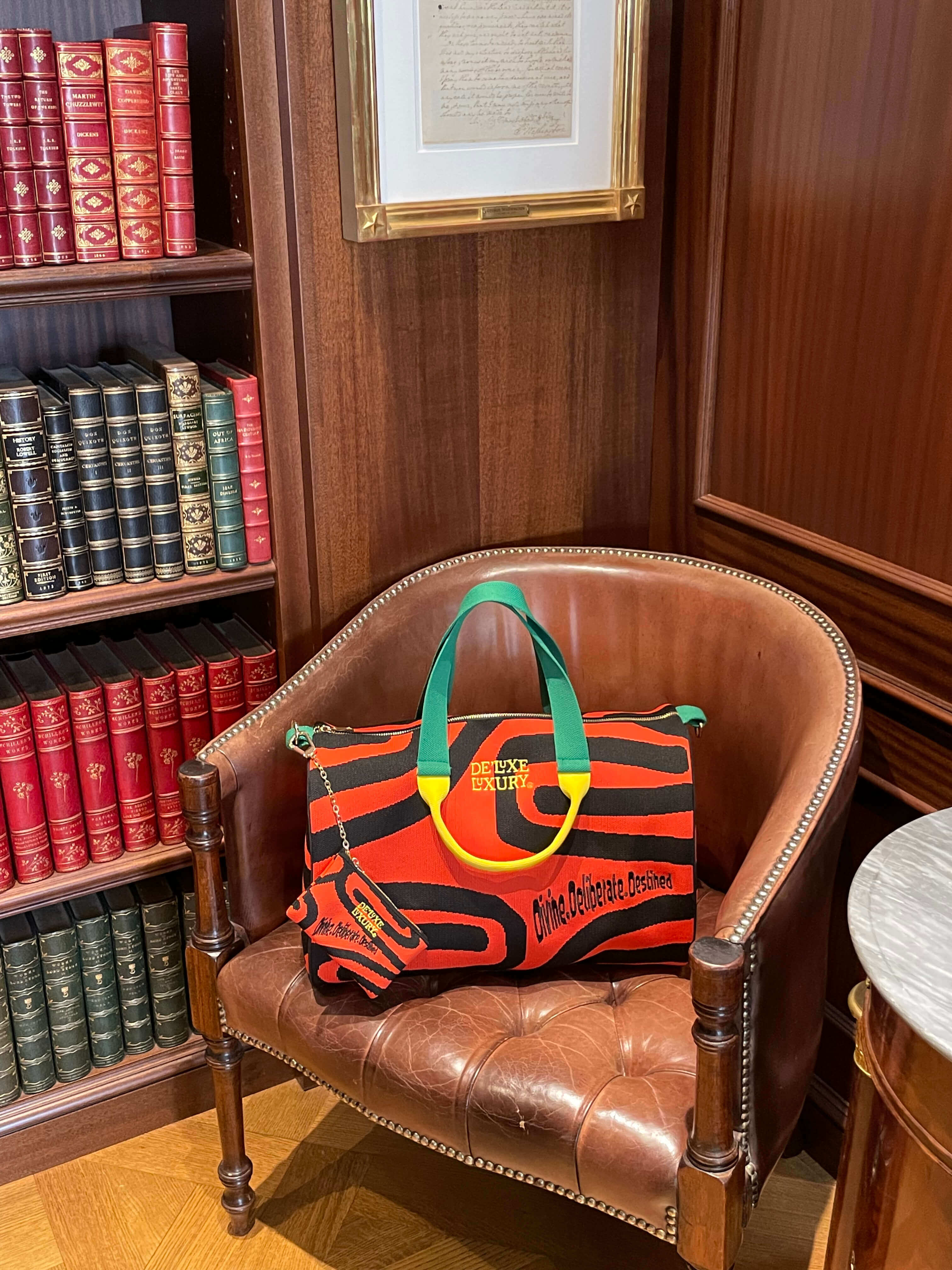 De'Luxe Luxury Scarab Journey 40 sitting in a brown leather chair in library