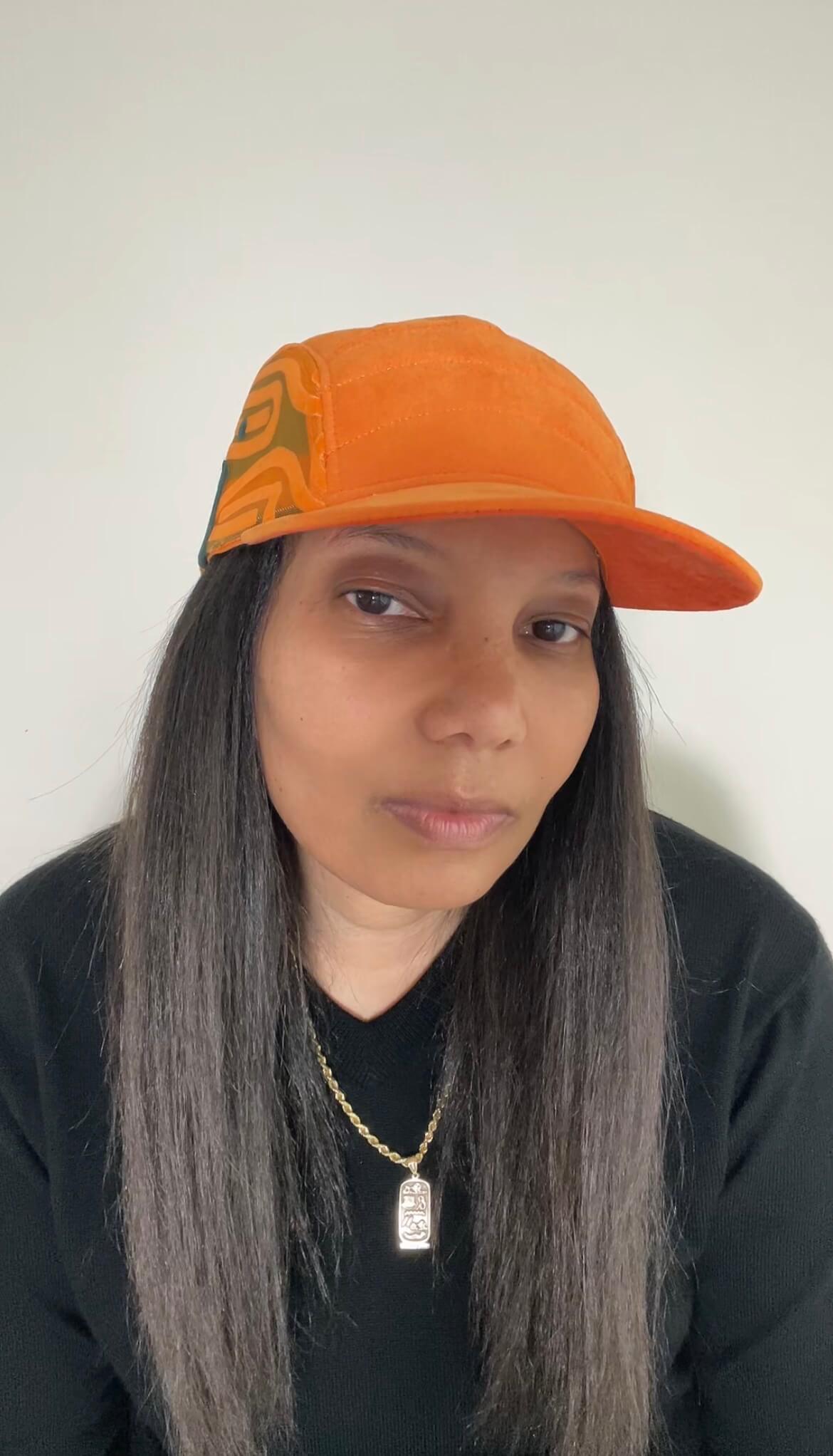 A woman with long dark hair wearing the Maverick hat in light amber with scarab path patterns on side