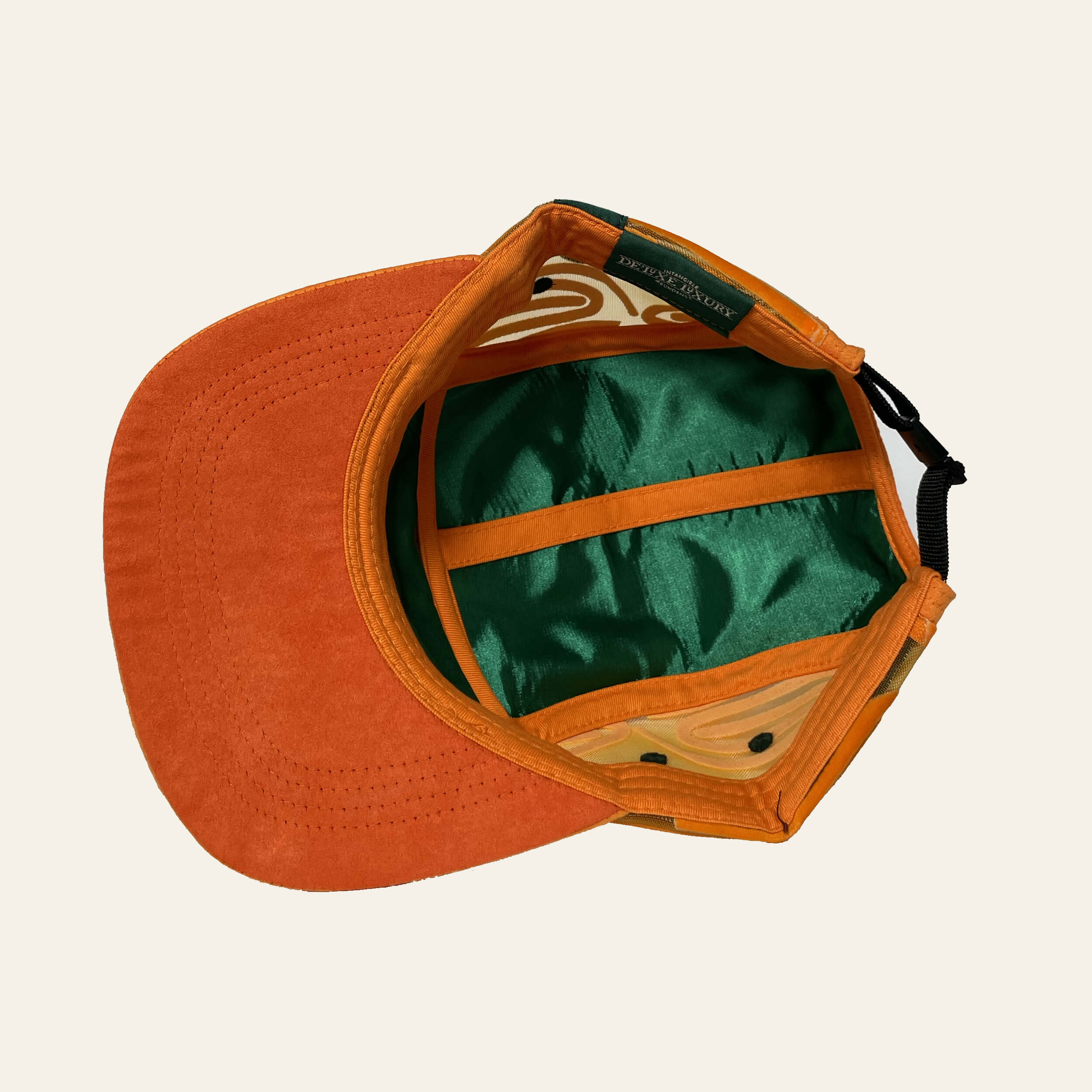 De'Luxe Luxury Maverick 5 panel camper hat inside view with emerald satin lining and suede like under brim in deep amber